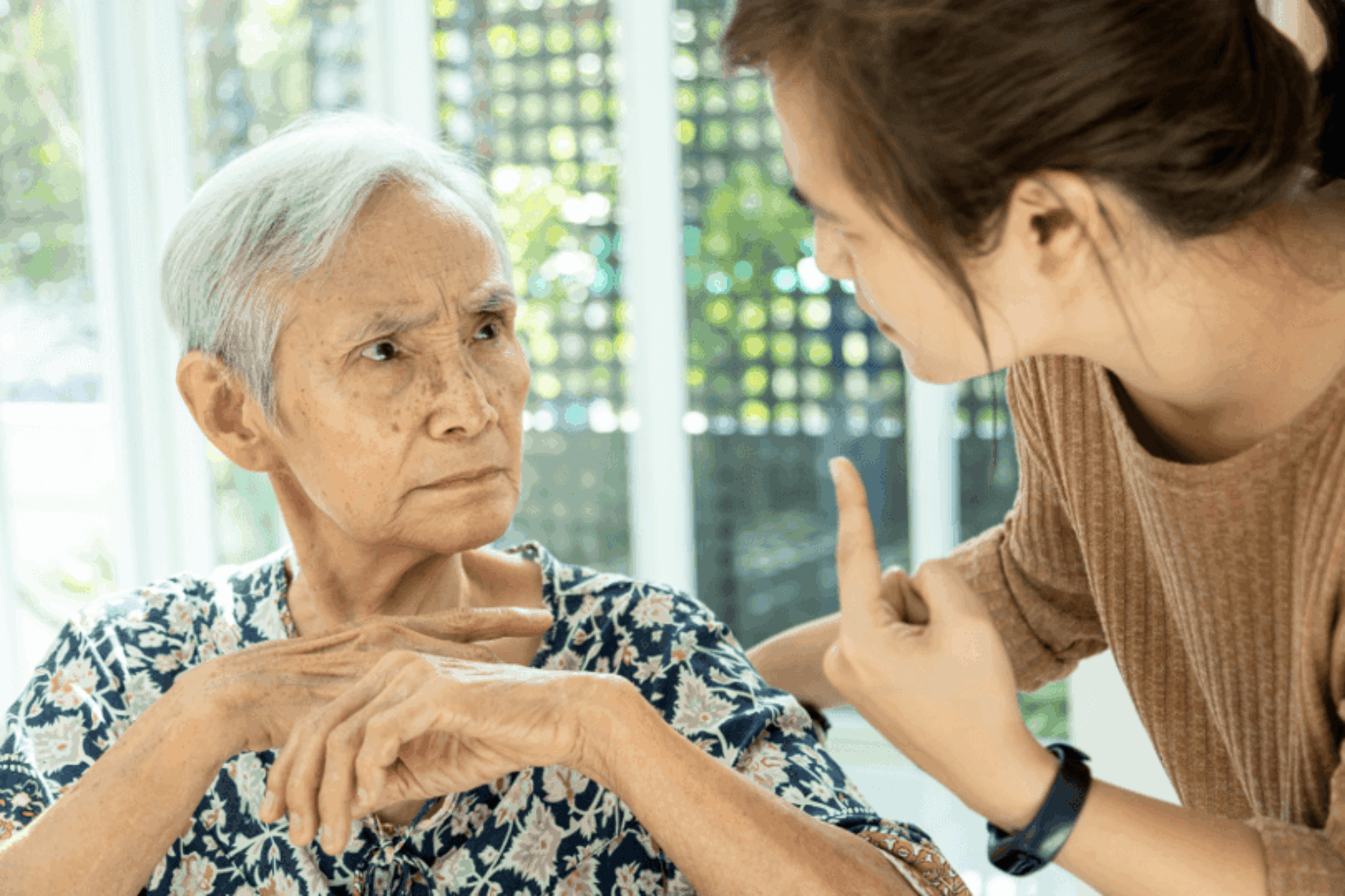 Older adult woman looking at a relative with a confused, almost angry look on her face.