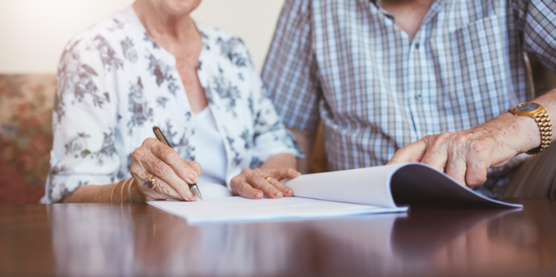 Older adult couple signing paper will.