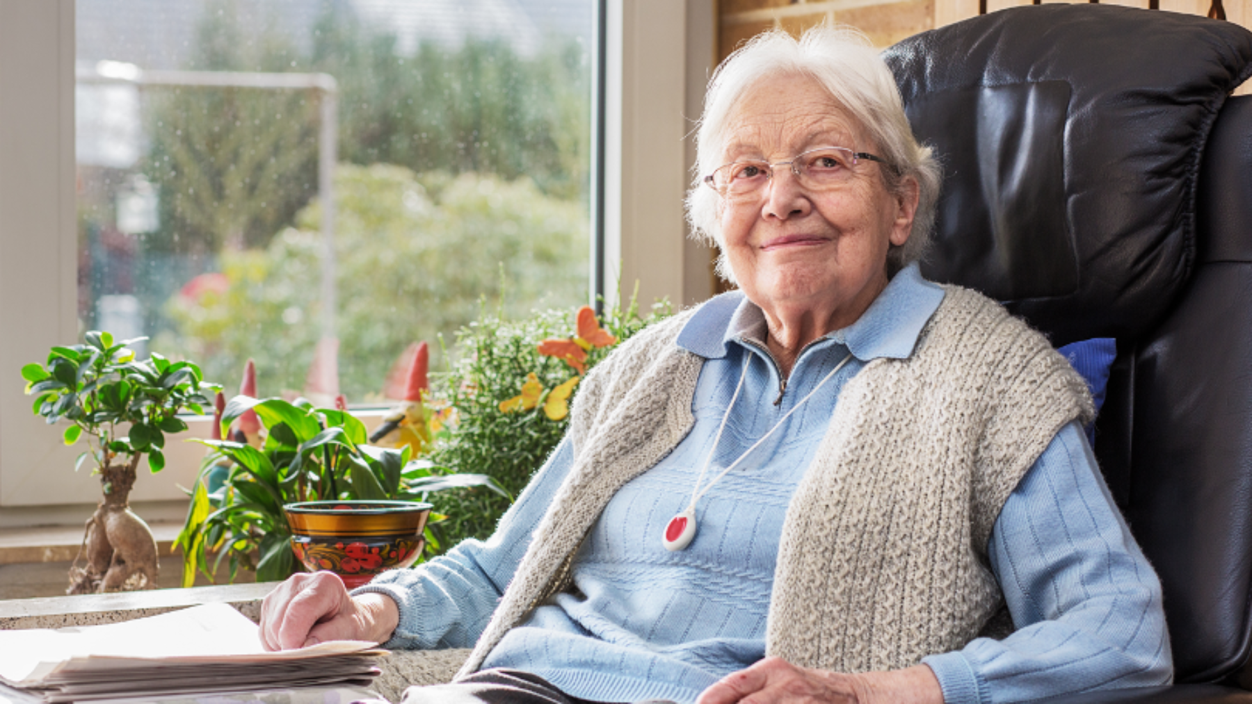 Older adult woman sitting in a recliner near a picture window.